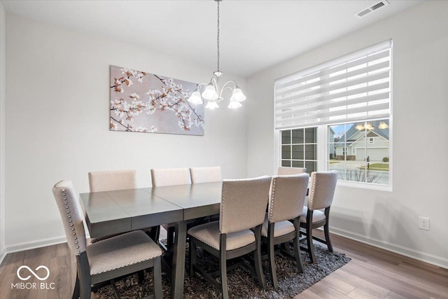 dining area featuring wood-type flooring and an inviting chandelier