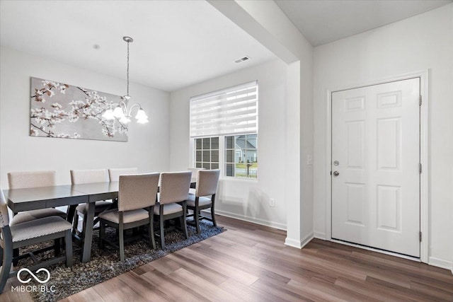 dining area featuring dark hardwood / wood-style floors and an inviting chandelier