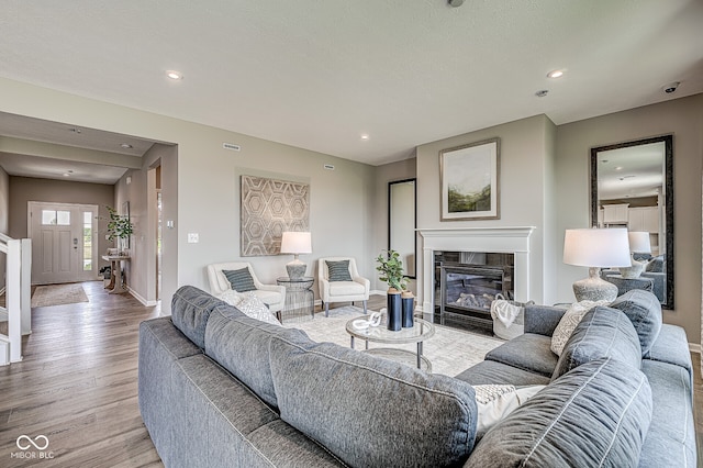 living room with light wood finished floors, a fireplace with flush hearth, and recessed lighting