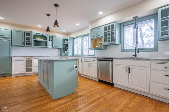 kitchen with dishwasher, sink, a kitchen island, pendant lighting, and white cabinets