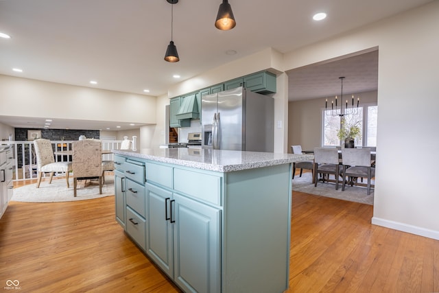 kitchen featuring stainless steel refrigerator with ice dispenser, light stone counters, a chandelier, light hardwood / wood-style floors, and hanging light fixtures