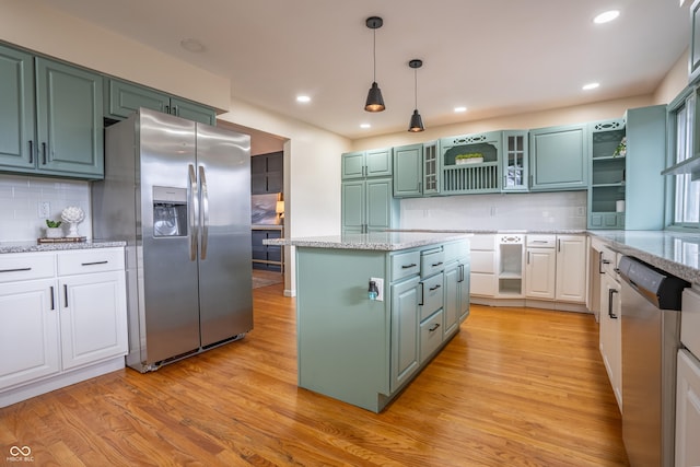 kitchen featuring backsplash, green cabinetry, a kitchen island, white cabinetry, and stainless steel appliances