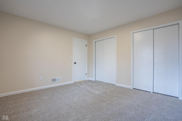 unfurnished bedroom with carpet flooring and two closets