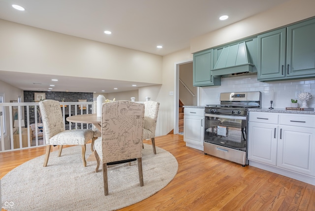 kitchen featuring gas range, tasteful backsplash, light hardwood / wood-style flooring, and custom range hood