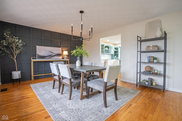 dining room with light hardwood / wood-style flooring and an inviting chandelier