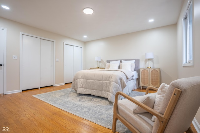 bedroom with light wood-type flooring and two closets