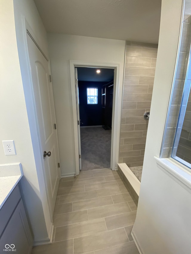 bathroom featuring a tile shower and vanity