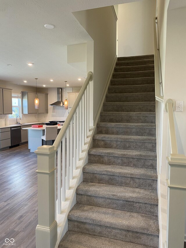 staircase featuring hardwood / wood-style floors, sink, and a textured ceiling