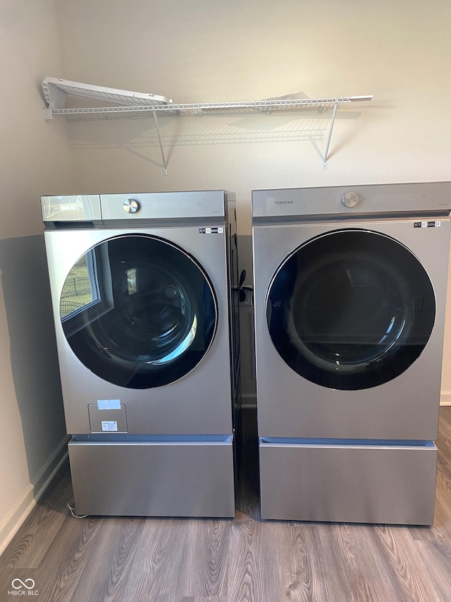 clothes washing area with hardwood / wood-style floors and independent washer and dryer