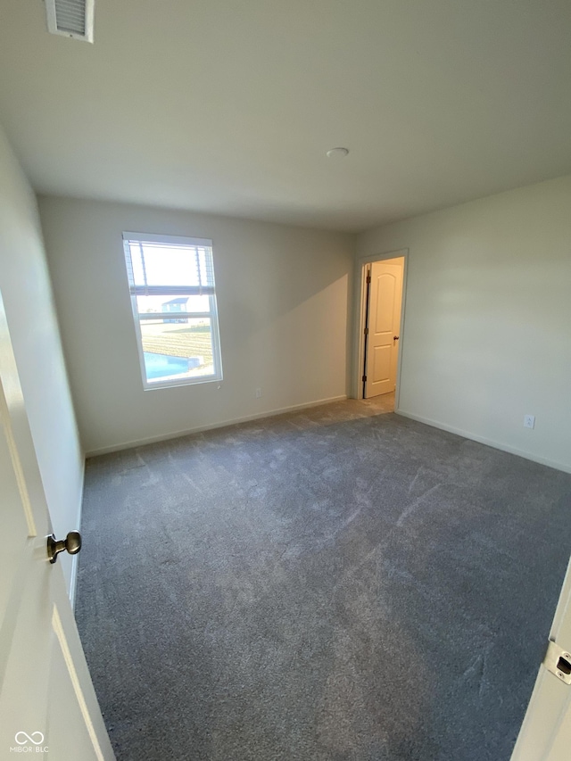 unfurnished room featuring dark colored carpet