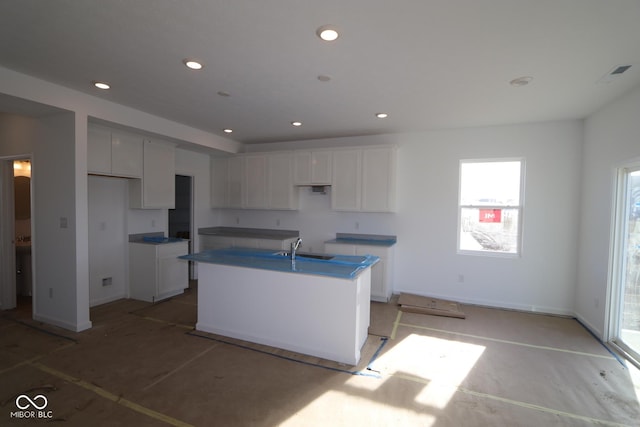 kitchen featuring white cabinets, sink, and an island with sink