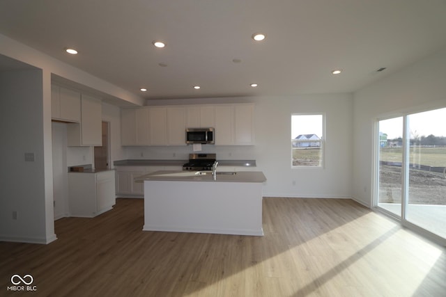 kitchen featuring sink, white cabinets, a kitchen island with sink, light hardwood / wood-style floors, and stainless steel appliances