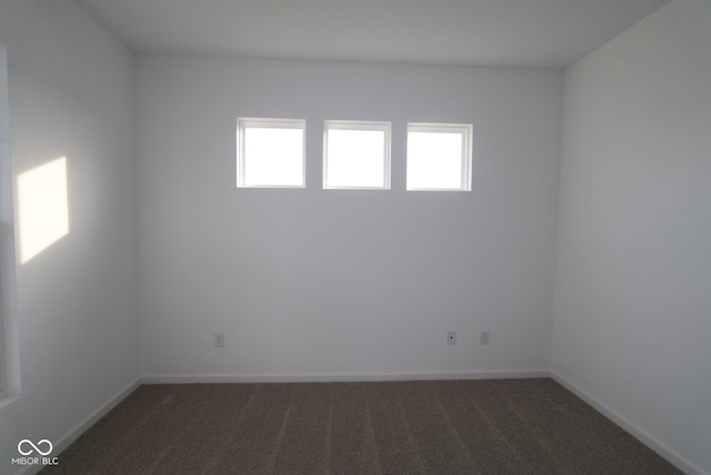 unfurnished room featuring dark carpet