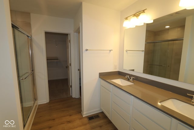 bathroom with hardwood / wood-style flooring, vanity, and a shower with door