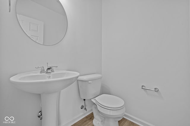 bathroom with wood finished floors, toilet, and baseboards