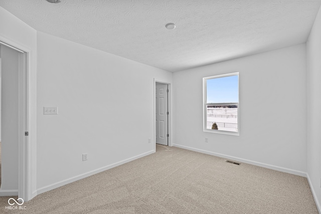 carpeted empty room featuring a textured ceiling, visible vents, and baseboards