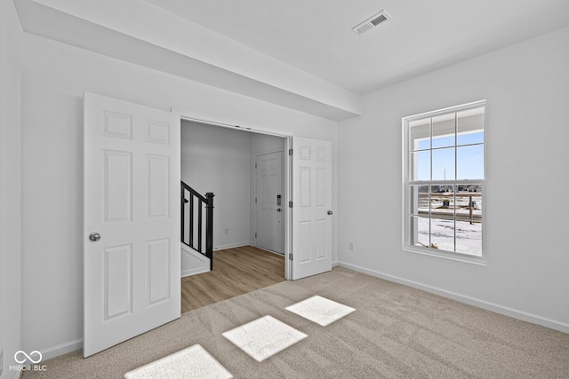 unfurnished bedroom featuring carpet flooring, visible vents, and baseboards