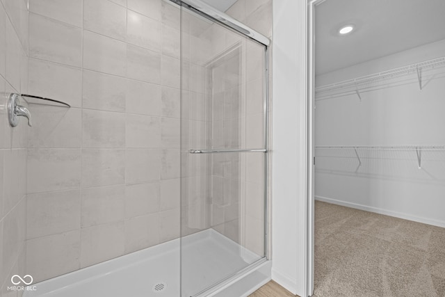 bathroom with a stall shower, a walk in closet, and baseboards