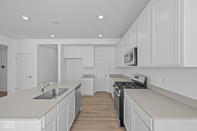 kitchen featuring stainless steel appliances, a sink, light wood-style flooring, and recessed lighting