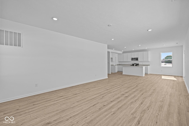 unfurnished living room with recessed lighting, light wood-type flooring, visible vents, and baseboards