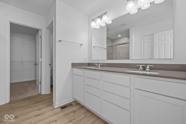 full bathroom featuring a stall shower, visible vents, a sink, and wood finished floors