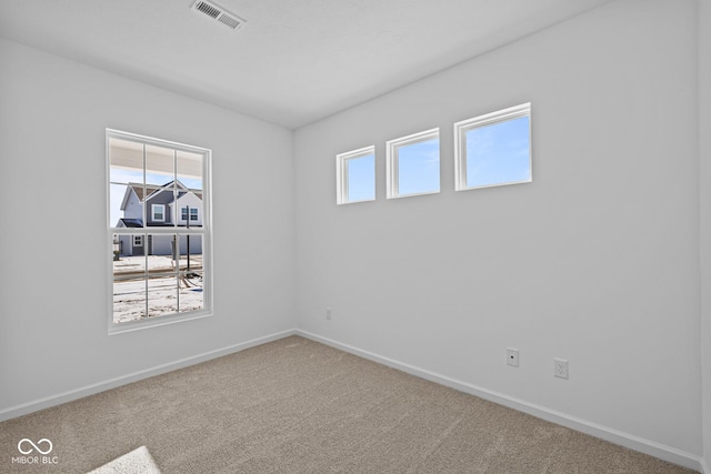 spare room featuring carpet, visible vents, and baseboards