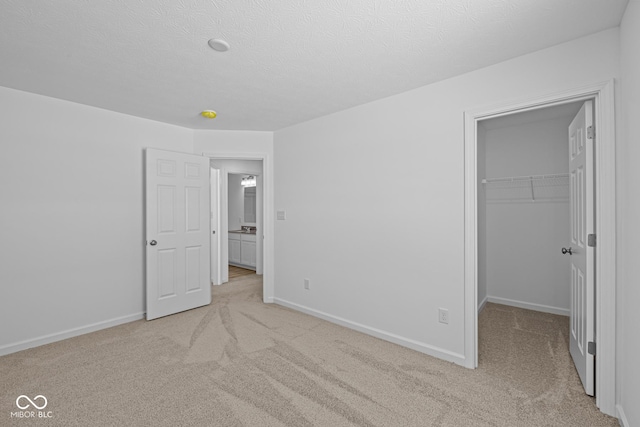 unfurnished bedroom featuring light carpet, a closet, a walk in closet, and baseboards