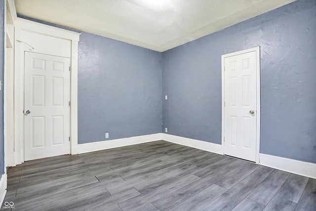 unfurnished room with hardwood / wood-style floors and a textured ceiling