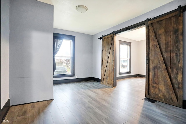 unfurnished room with light wood-type flooring and a barn door