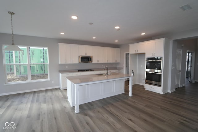 kitchen with sink, decorative light fixtures, a center island with sink, stainless steel appliances, and white cabinets