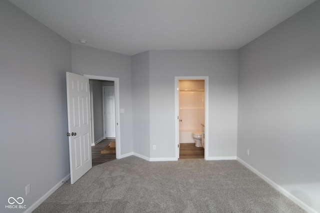 unfurnished bedroom with connected bathroom and carpet flooring