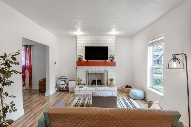 living room featuring a fireplace, a textured ceiling, and light wood-type flooring