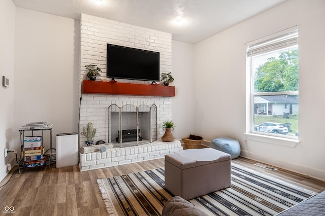 living room with a fireplace, wood-type flooring, and a textured ceiling