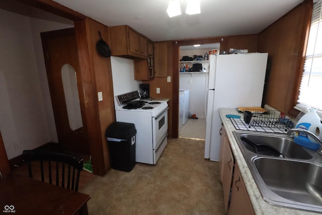 kitchen featuring washer / clothes dryer, light carpet, sink, and white appliances