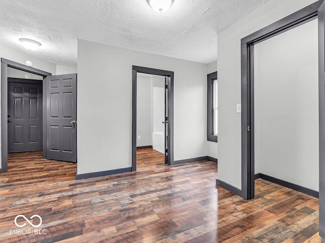 unfurnished bedroom featuring a textured ceiling and dark hardwood / wood-style floors