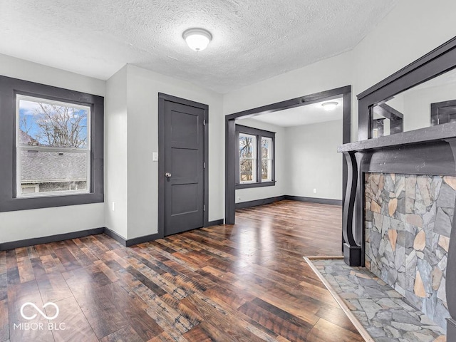 unfurnished living room featuring a textured ceiling and dark hardwood / wood-style flooring