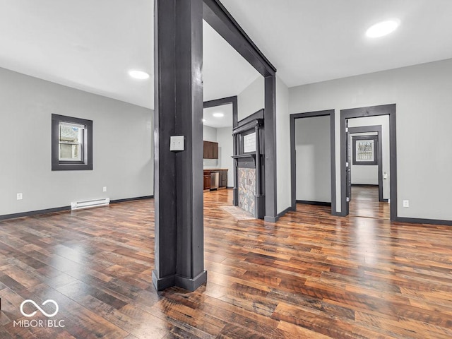 unfurnished living room featuring a baseboard heating unit and dark hardwood / wood-style flooring