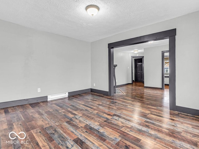 empty room featuring a textured ceiling and dark hardwood / wood-style floors