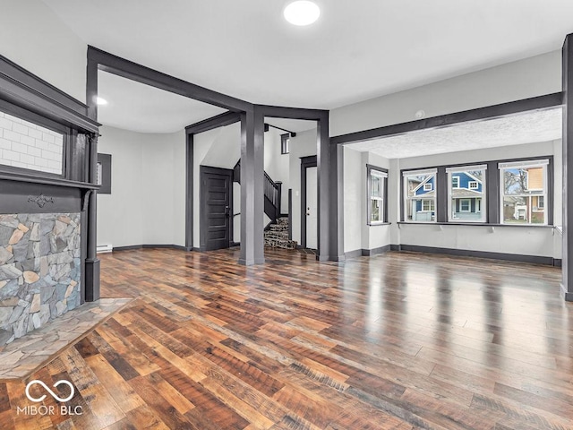 unfurnished living room with dark hardwood / wood-style flooring and baseboard heating