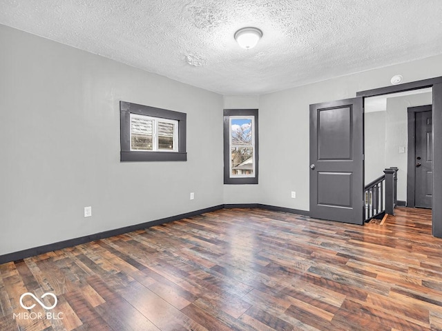 empty room featuring dark wood-type flooring and a textured ceiling