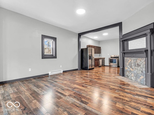 unfurnished living room featuring baseboard heating and hardwood / wood-style floors