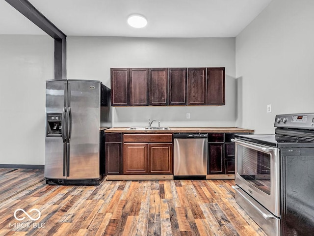 kitchen featuring sink, light wood-type flooring, dark brown cabinets, and appliances with stainless steel finishes