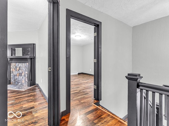 hallway featuring a baseboard heating unit, dark hardwood / wood-style flooring, and a textured ceiling