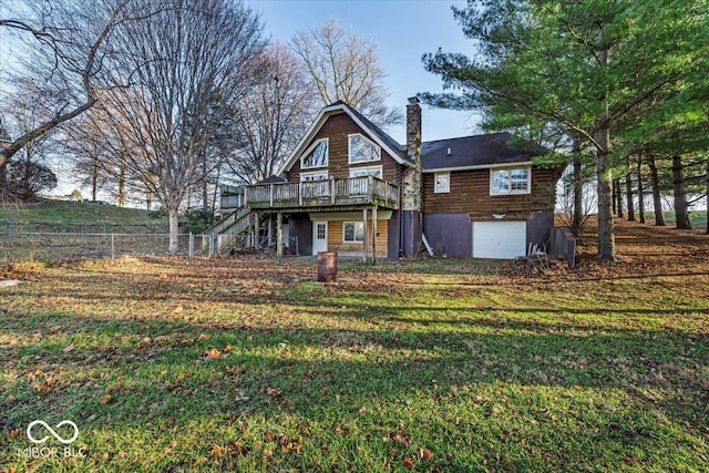 rear view of property with a garage, a lawn, and a wooden deck