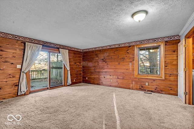 carpeted empty room featuring a textured ceiling and wood walls