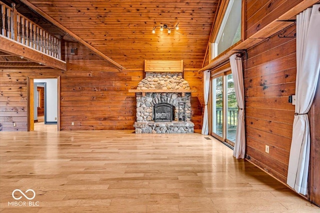 unfurnished living room with hardwood / wood-style floors, wood walls, wooden ceiling, and a fireplace