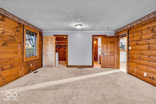 unfurnished bedroom featuring multiple windows, a walk in closet, a closet, and light carpet