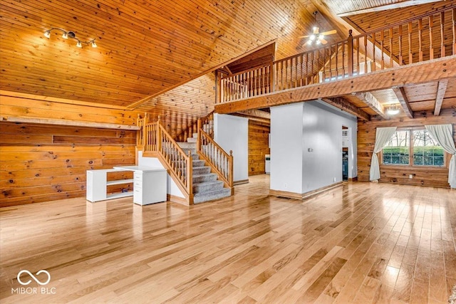 unfurnished living room with wooden ceiling, high vaulted ceiling, wooden walls, ceiling fan, and wood-type flooring