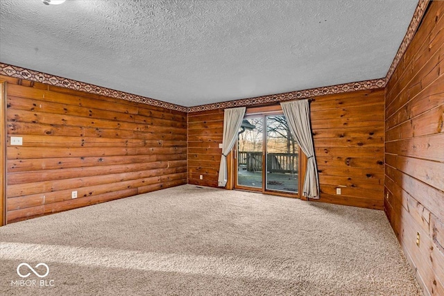 carpeted empty room featuring wooden walls and a textured ceiling