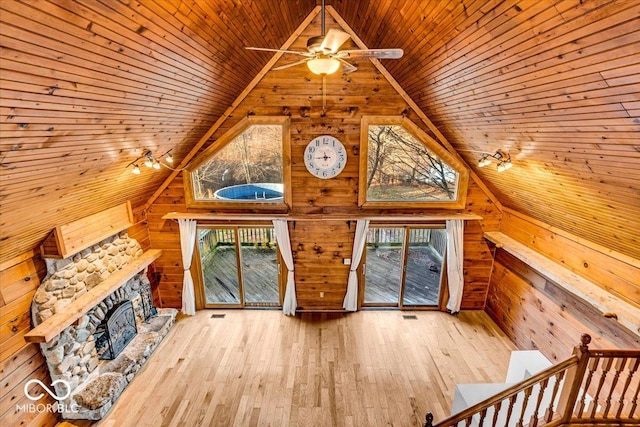 unfurnished living room featuring a healthy amount of sunlight, wooden ceiling, wooden walls, and light hardwood / wood-style floors